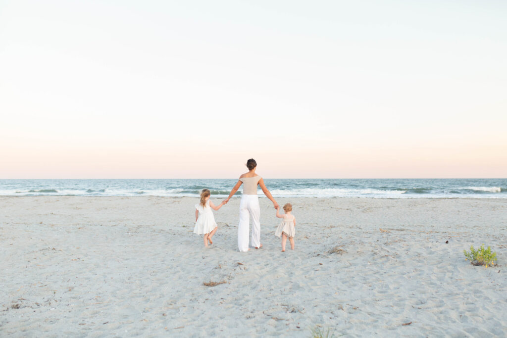 Mother walking in the sand with her children on the beach during an extended family photo session