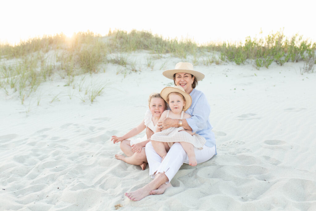 Grandmother and grandchildren sitting on the beach at sunset